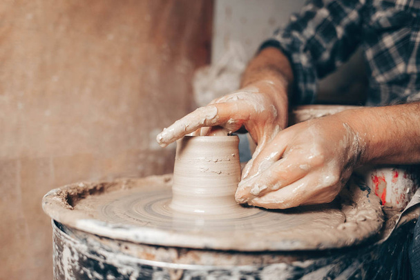 Man forms a white clay product on a pottery wheel closeup - Photo, Image