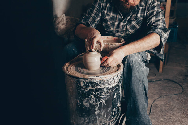 陶芸家はワークショップで陶芸ホイールに取り組んでいます - 写真・画像