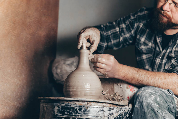 Master works on the potter's wheel creating a jug of clay - Photo, Image