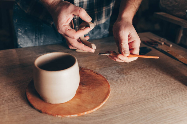 Potter glues ears to a cup. Process of creating a ceramic cup - 写真・画像