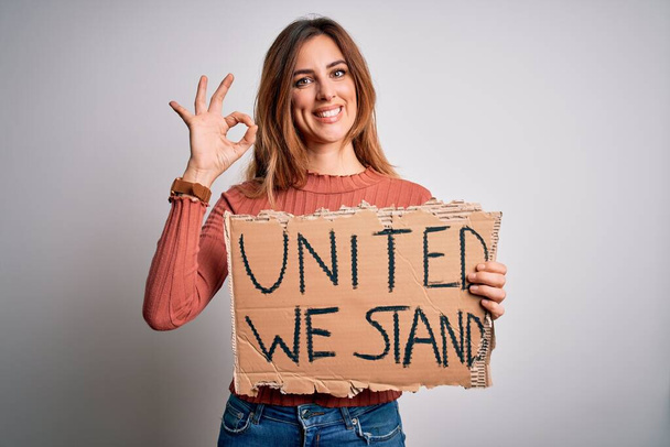 Beautiful brunette woman holding banner with united we stand lettering - 写真・画像