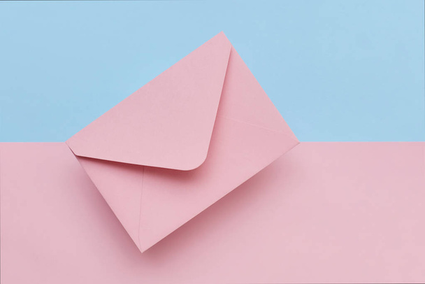 Pink envelope on the double colored pink and blue background. Mail concept - Photo, Image