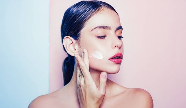 Taking good care of her skin. Beautiful woman spreading cream on her face. Skin cream concept. Facial care for female. Keep skin hydrated regularly moisturizing cream. Fresh healthy skin concept - Zdjęcie, obraz