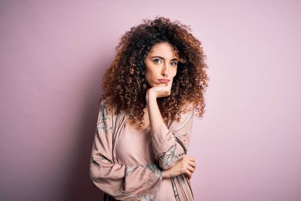 Young beautiful woman with curly hair and piercing wearing casual pink t-shirt thinking looking tired and bored with depression problems with crossed arms. - Fotoğraf, Görsel