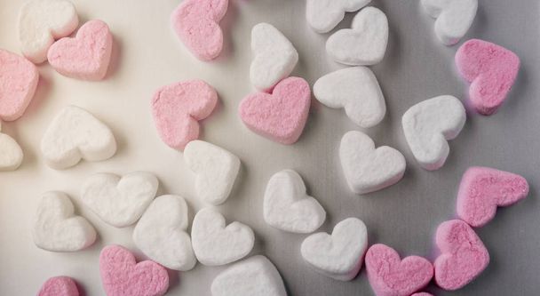 pink and white heart-shaped marshmallows evenly laid out on gray aluminum background - Photo, image
