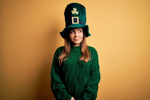Young beautiful brunette woman wearing green hat on st patricks day celebration smiling looking to the side and staring away thinking. - Photo, Image