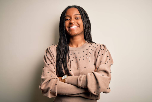 junge afrikanisch-amerikanische Modefrau steht lässig über braunem, isoliertem Hintergrund und lächelt mit verschränkten Armen in die Kamera. positive Person. - Foto, Bild