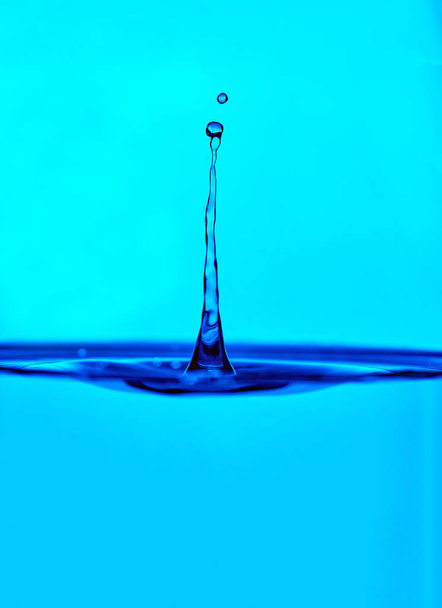 gota de agua salpicadura en un vidrio de color azul - Foto, imagen