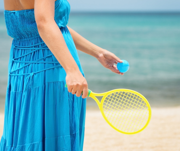 Woman in blue dress playing tennis on the beach - Photo, Image