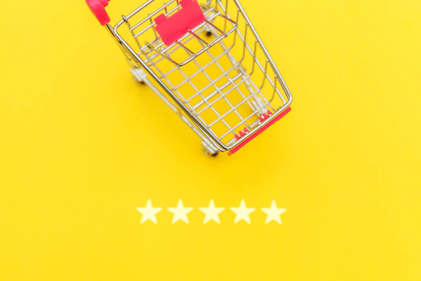 Маленький продуктовый супермаркет толкает картон для покупки игрушки с колесами и 5 звездами рейтинга изолированы на желтом фоне. Концепция оценки и обзора покупок розничных потребителей онлайн
. - Фото, изображение