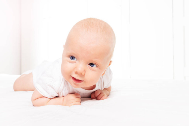 Smiling baby infant boy learn laying on the belly - Foto, afbeelding