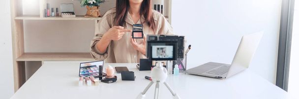kaunis aasialainen nainen ammatillinen kauneus vlog tai bloggaaja esittää kosmetiikkaa ja soveltamalla meikkiä etukamerassa videon tallentamiseksi
 - Valokuva, kuva