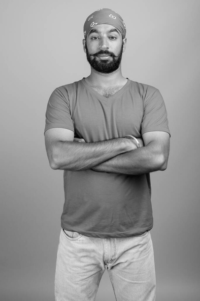 Зйомки молодого вродливого бородатого індійського чоловіка на сірому фоні в чорно-білому - Фото, зображення