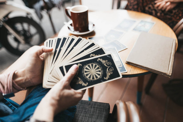 Woman is reading Tarot cards on the table in cafe - Fotoğraf, Görsel