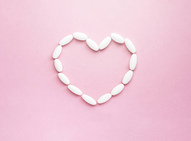 Heart shape made from pills for therapy, concept of treatment and health care on soft pink - Photo, Image