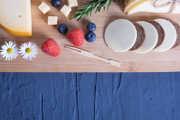 on a wooden board breakfast, sliced cheese with berries  - Fotografie, Obrázek