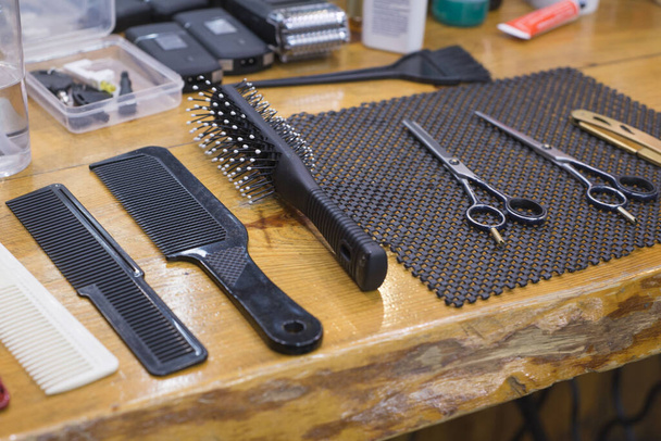 Nahaufnahme eines Friseurs am Arbeitsplatz. Auf dem Tisch liegen Kämme und Haarschneidemaschinen. Friseurladen - Foto, Bild