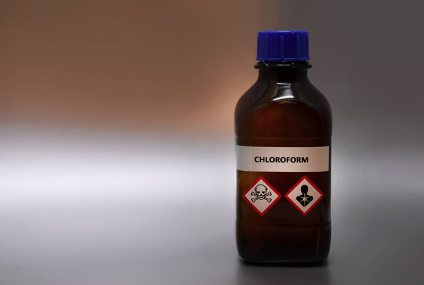 Chloroform in brown laboratory bottle stock images. A bottle of chloroform with inscription. Brown lab bottle. Brown glass container. Phial with warning pictograms on a silver background - Photo, Image