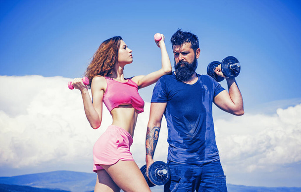 Athletic couple in sportswear pumping up arm and back muscles with dumbbells. Beautiful attractive fitness friends. Abs fitness woman body. Female model in sportswear exercising outdoors. Sporty - Foto, Imagem
