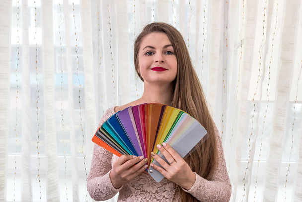 улыбающийся дизайнер показывает цветные образцы в ее руках - Фото, изображение