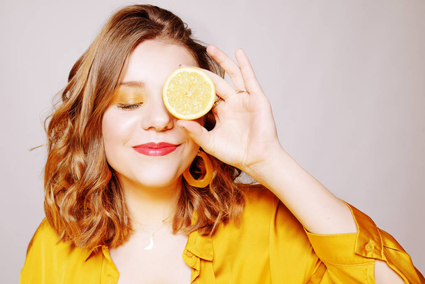 Portrait of a girl with a lemon. A girl in a bright yellow dress - Фото, зображення