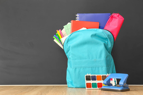 Schulrucksack mit Schreibwaren auf Tisch im Klassenzimmer - Foto, Bild