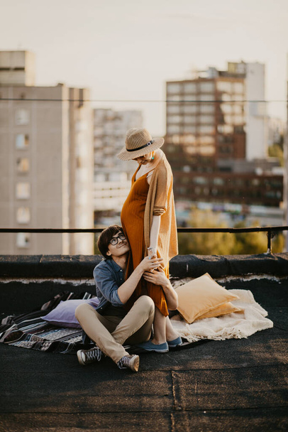 happy young couple having fun  on the building rooftop. Redhead Pregnant women with her husband at sunset time - 写真・画像
