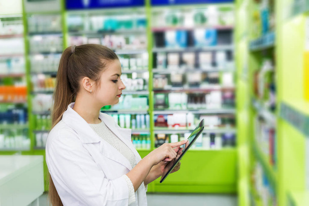 Pharmacist looking something in tablet, pharmacy and drugstore - Фото, изображение
