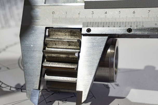 A vernier caliper measures the length of a gear tooth lying on a - Fotoğraf, Görsel