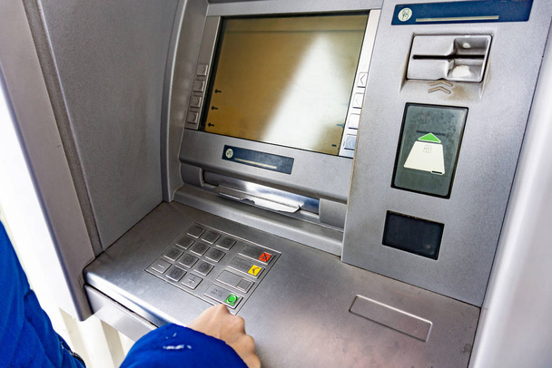Μια γυναίκα σε ΑΤΜ πατάει ένα κουμπί για να κάνει ανάληψη μετρητών.. - Φωτογραφία, εικόνα