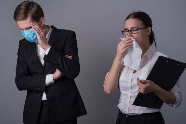 Porträt zweier junger Geschäftsleute in Businesskleidung. verdeckt der Maskierte sein Gesicht mit der Hand, aus Angst vor einer Infektion durch ein krankes Mädchen. der in ein Taschentuch niest. - Foto, Bild