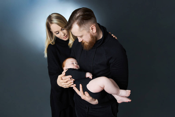 Man and a woman hold a baby in their arms. Portrait of a married - Foto, afbeelding