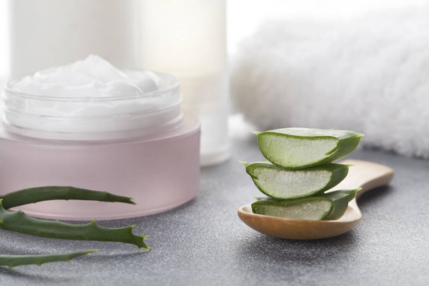 Aloe vera sliced leaves and natural cream, lotion, tonic and towel on white background - Photo, Image