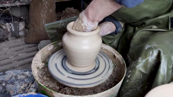 As mãos de um oleiro em uma roda de cerâmica fecham-se. Antiga arte tradicional, artesanal, produção de argila e cerâmica. Oficina de cerâmica em luz suave subjugada
 - Filmagem, Vídeo