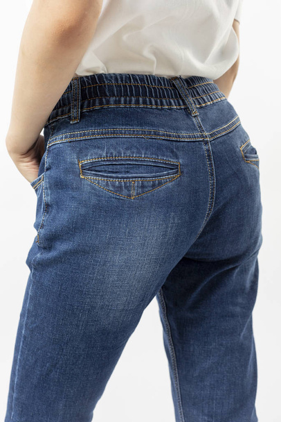 girl in jeans shows off jeans on white background close up, blue jeans - 写真・画像