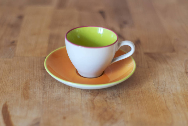 Порцелянова чашка з тарілкою на дерев'яному столі
 - Фото, зображення