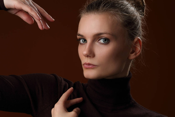 Beautiful girl in a maroon turtleneck on a brown background - Photo, image