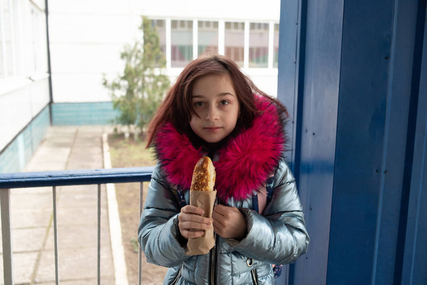 Κορίτσι με ψωμί στο χέρι. Φρεσκοψημένο ψωμί στα χέρια. . Το παιδί κρατάει πολύ ψωμί σε χέρια απομονωμένο. - Φωτογραφία, εικόνα