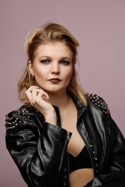 Woman blonde in leather jacket looking at camera isolated in studio - Foto, imagen