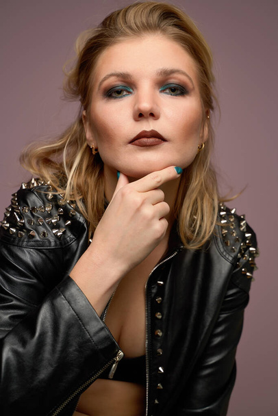 Woman blonde in leather jacket looking at camera isolated in studio - Foto, Imagen