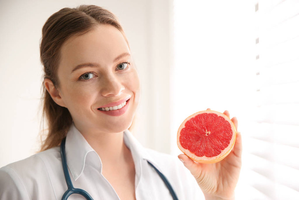 Nutritionist with grapefruit near window in office - Фото, изображение
