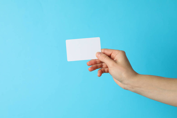 Female hand holding empty business card on blue background - Фото, изображение