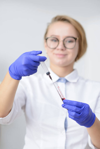  血液サンプルおよび試験管が付いている注射器を握るラテックス手袋の医者 - 写真・画像