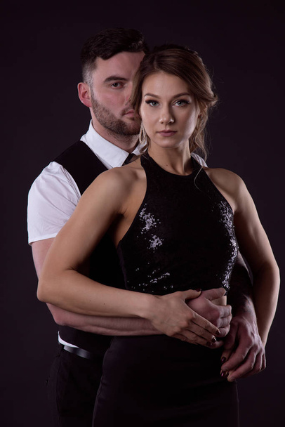Loving couple in black clothes on a black background - Foto, afbeelding