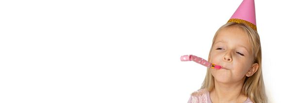 Niño pequeño con sombrero rosa soplando en la pipa de cumpleaños sobre fondo blanco. Copiar espacio, maqueta, banner de plantilla
. - Foto, imagen