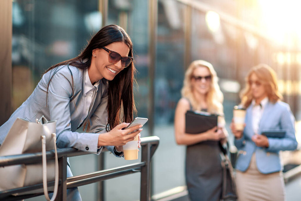 Mulher sorrindo atraente segurando telefone ao ar livre
  - Foto, Imagem