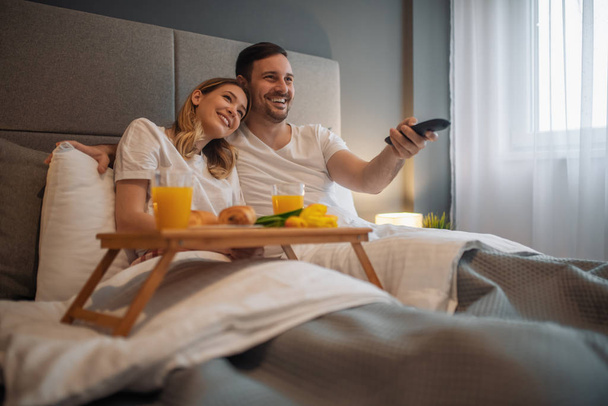 Пара смотрит телевизор в своей постели дома
 - Фото, изображение