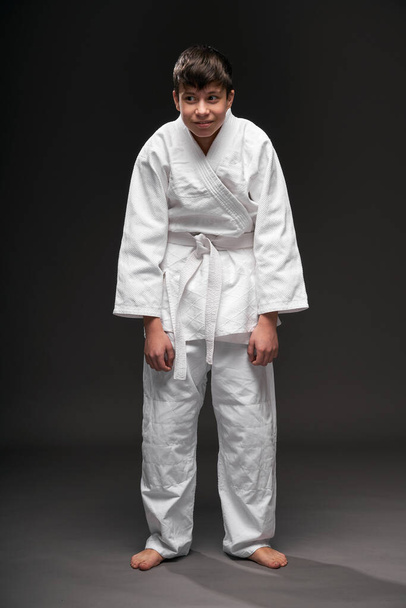 un adolescent vêtu de vêtements d'arts martiaux pose sur un fond gris foncé, ayant la dépression, concept sportif
 - Photo, image
