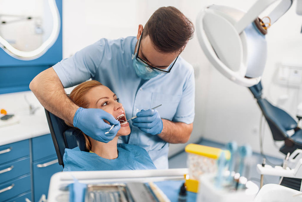 Dentysta, badając pacjenta zębów w gabinecie stomatologicznym  - Zdjęcie, obraz