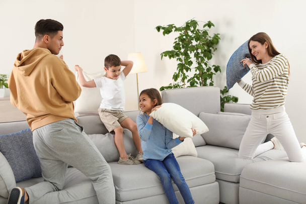 Happy family having pillow fight in living room - 写真・画像
